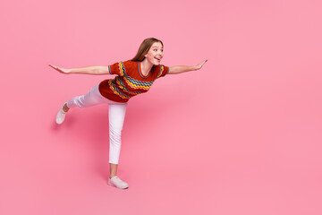 Wall Mural - Full length profile portrait of overjoyed girl stand one leg arms wings look empty space isolated on pink color background