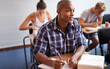 © M Moller/peopleimages.com - Black man, student and writing with book in classroom for studying, reading or summary at university. African male person or young academic writer with notebook for assignment, test or exam at campus