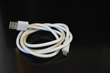 White long wire for computer and office equipment, Usb cable microusb connector on a black glossy surface.