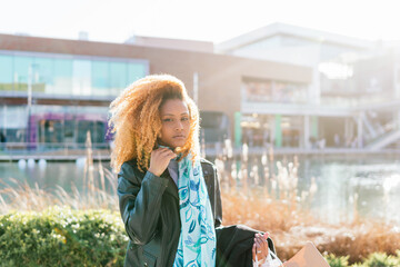 Canvas Print - A black girl with afro hair holds shopping bags outside a shopping center, looking at camera