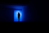 Fototapeta  - Une silhouette de femme bleu debout dans un décor architectural sombre et bleu