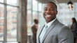 © MP Studio - A confident businessman in a grey suit with a friendly smile, standing in a corporate office environment.