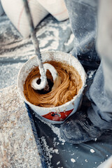 Wall Mural - Professional worker mixes two chemical compounds in the metal bucket using the mixer