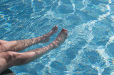 Fototapeta Łazienka - Man relaxing in swimming poll. Man legs in water.