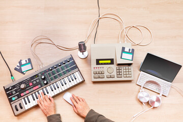 Wall Mural - top view of male music producer, composer, arranger hands arranging a hit song on synthesizer keyboard, sequencer, laptop computer. music production or recording concept