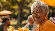 © Maelgoa - A happy elderly black woman enjoying a picnic with her friends in her garden