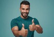 A smiling man in a teal shirt gives double thumbs up, radiating friendliness and confidence.
