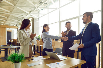 Wall Mural - Successful collaboration as a diverse group of business people in the office exchange handshake. This symbolic gesture reflects completion of successful work, partnership and teamwork.