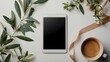 mock-up top view shot tablet empty screen with coffee cup, beige ribbon, and olive leaves branch in white table background