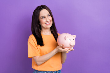 Sticker - Photo of dreaming brunette business lady holding piggy bank looking empty space imagine expand her team isolated on violet color background