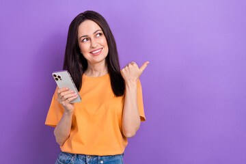 Wall Mural - Portrait of dreamy girl wear oversize t-shirt holding smartphone look directing at sale empty space isolated on violet color background