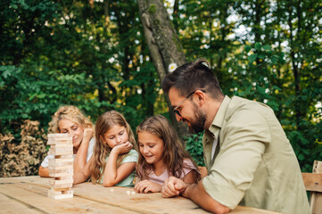 Family playing cognitive game in nature on picnic.