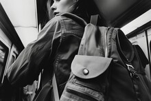 Monochromatic Shot Of A Young Woman With A Backpack Standing On A Subway Train