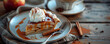 A slice of apple pie with vanilla ice cream and caramel sauce. A fork and a spoon on a plate. A cup of tea and a cinnamon stick on a brown background Top view space to copy.