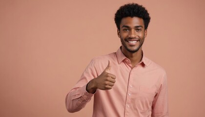 Wall Mural - A joyful young man in salmon shirt showing thumbs up, peach background. He exudes happiness and agreement.