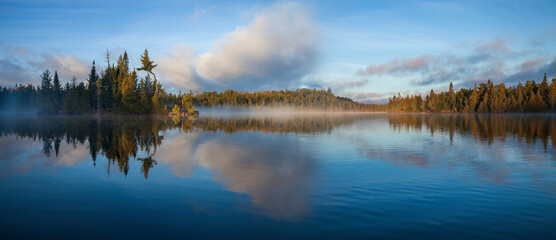 Wall Mural - panorama of blue lake in northern minnesota with an island and pines on a foggy september morning