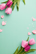 Mother's day freshness: spring's gentle touch. Top view vertical shot of tulips, pink paper hearts and scattered confetti on teal background with space for personalized messages and wishes