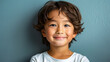 Smiling Asian boy with wavy hair against blue wall