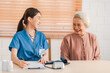 Medical health insurance service, Asian caregiver doctor examine older patient use blood pressure gauge. Young woman therapist nurse nursing home taking care to senior elderly woman