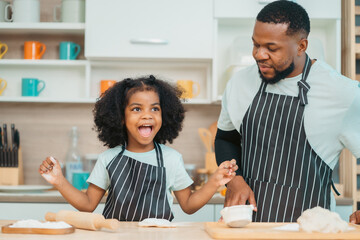 Wall Mural - happy child family with father or mother cooking fun together for bakery bread meal in kitchen, young African little kid daughter girl and parent in love childhood lifestyle at home for food homemade