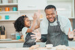 © chokniti - happy child family with father or mother cooking fun together for bakery bread meal in kitchen, young African little kid daughter girl and parent in love childhood lifestyle at home for food homemade