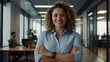 © LIFE LINE - Portrait of happy and successful business woman, boss in shirt smiling and looking at camera inside office with crossed arms, Hispanic woman with curly hair in corridor