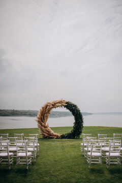 Decorations of a wedding ceremony on a green lawn. Grandiose large and stylish arch and chiavari chairs