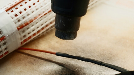 Master electrician heating insulation around copper wires with a special tool. Creative. Workshop and equipment details.