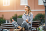 Fototapeta Tulipany - Woman meditating with laptop on urban bench