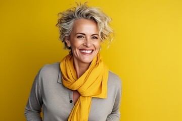 Wall Mural - Portrait of a happy mature woman with yellow scarf over yellow background