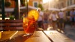 Served cocktail of Aperol spritz with orange slice and straw placed on wooden table of sidewalk cafe in Italy : Generative AI