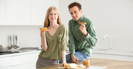 Sticker - Happy young couple with tasty toasts of nut butter in kitchen