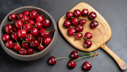 Poster - Bowl and board with sweet cherries on black background, top view; high quality photo