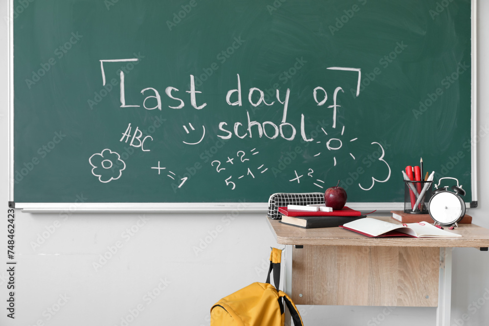 Text LAST DAY OF SCHOOL with drawings on blackboard in classroom