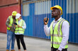 © offsuperphoto - worker or engineer using walkie talkie and talking about work in containers warehouse storage