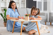 © Pixel-Shot - Happy mother with her little daughter sitting on floor and drawing at table in living room