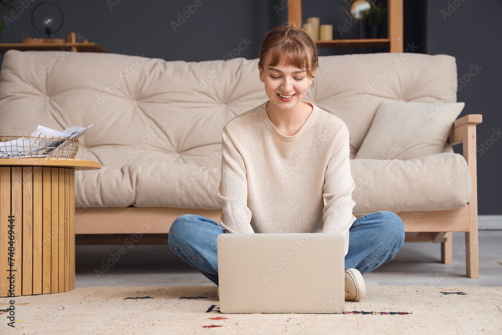 Young woman using laptop on floor at home