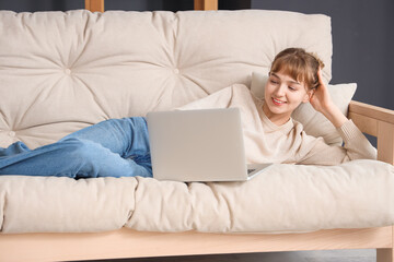 Young woman using laptop on sofa at home