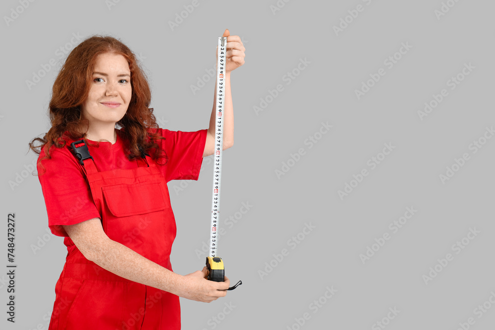 Young woman with measuring tape on grey background