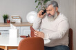 © Pixel-Shot - Portrait of sad senior man with empty wallet talking by phone in kitchen