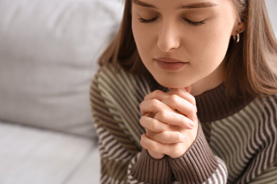 Young woman praying at home, closeup
