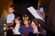 Close up of drama teacher holding play script with group of children on stage in background copy space