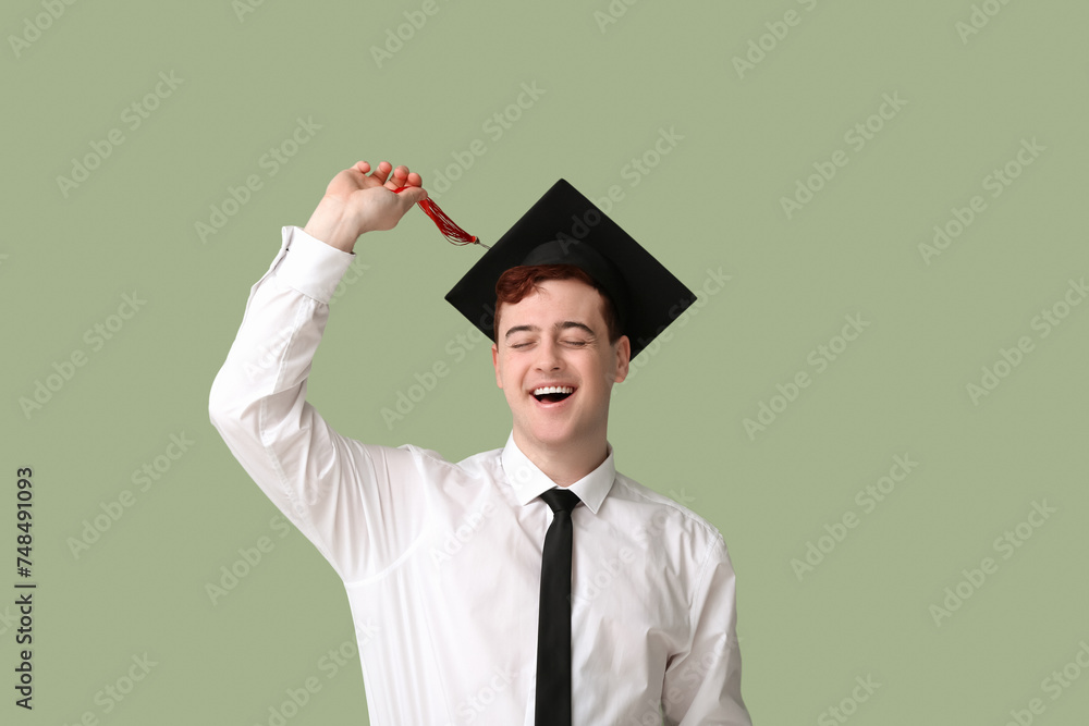 Happy male student in mortar board on green background