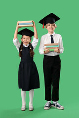 Canvas Print - Little children in graduation hats with books on green background. End of school year