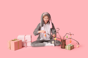 Wall Mural - Beautiful young happy woman in bunny costume with gift boxes and decorations on pink background. Easter celebration