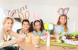 © Pixel-Shot - Little children in bunny ears making Easter crafts at table