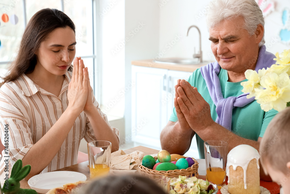Happy family praying before Easter dinner in kitchen