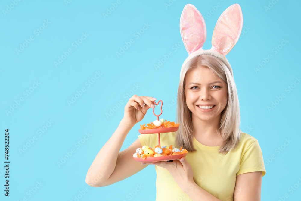 Beautiful woman in bunny ears with Easter eggs on blue background