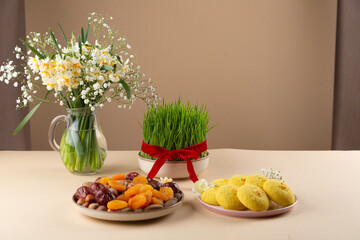 Wall Mural - Novruz table setting with green samani wheat grass with red ribbon, dried fruits, sweet pastry, candles, kelagai and blooming flowers, spring or new year celebration in Azerbaijan, copy space
