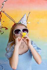 Wall Mural - Portrait of funny girl in birthday hat and bright confetti on yellow background. Celebration and party